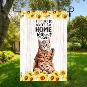 May include: A white wooden sign with a sunflower border and the text "A house is not a home without a cat." Three cats are stacked on top of each other, with the top cat looking at the viewer.