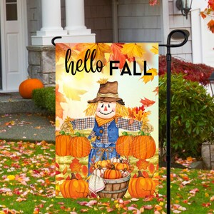 May include: A colorful fall-themed garden flag with a scarecrow holding pumpkins and the text "hello FALL".