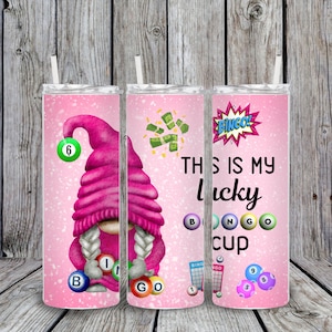 May include: Three pink and white tumbler cups with a gnome design. The gnome is holding bingo balls and there is a bingo card and money on the cups. The text on the cups says "This is my lucky bingo cup".