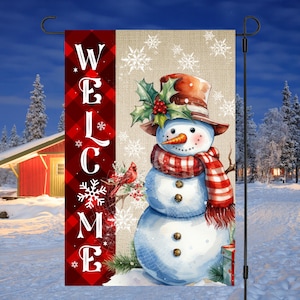 May include: A red and white plaid welcome sign with a snowman and cardinal in a winter scene. The snowman is wearing a red and white plaid scarf and a brown hat. The cardinal is perched on a branch with red berries.