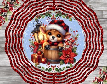 May include: Red and white striped metal wind spinner with a circular design. The center of the spinner features a cartoon deer wearing a red and black Santa hat, sitting in a wooden barrel. The deer is surrounded by holly and poinsettia.