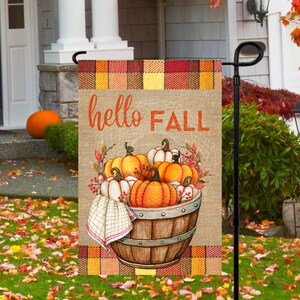 May include: A burlap garden flag with a plaid border. The flag features a basket of pumpkins with the text "hello FALL" in orange.