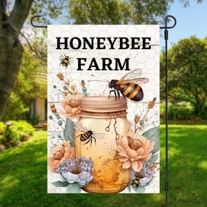 May include: A garden flag with a white background and a honeycomb pattern. The text "Honeybee Farm" is printed in black. A mason jar filled with honey is surrounded by flowers and bees.
