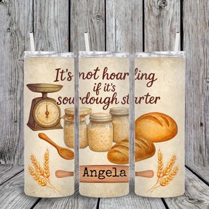 Puede incluir: Un vaso beige con pajita, con un diseño de acuarela de utensilios de panadería y pan. El texto dice: "No es acaparar si es masa madre". Incluye una balanza, tarros, una cuchara de madera y el nombre "Angela".