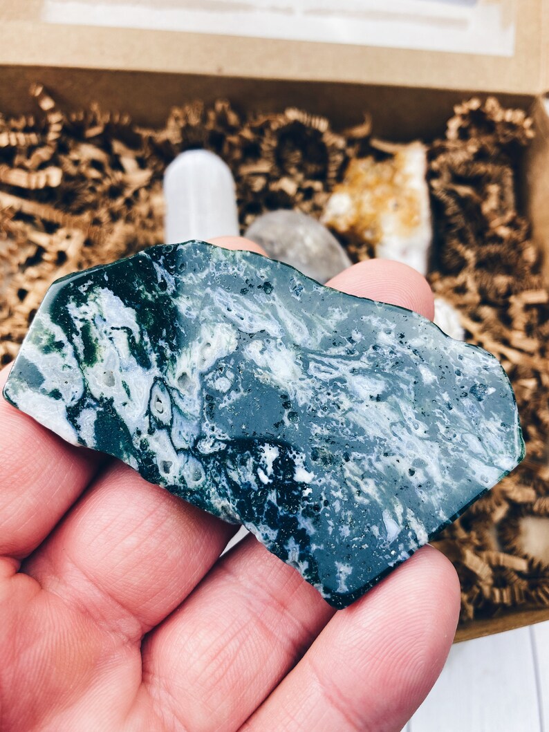Puede incluir: Una piedra de &aacute;gata verde y blanca con un patr&oacute;n de remolino. La piedra es lisa y pulida.