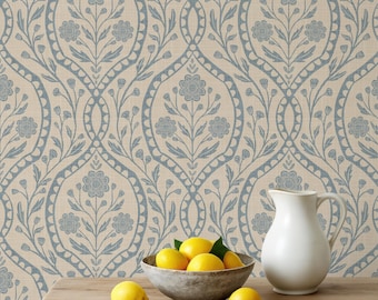 May include: A wooden table holds a gray bowl filled with yellow lemons, a white ceramic pitcher, and two loose lemons. The background features wallpaper with a repeating blue floral damask pattern on a light beige textured surface.
