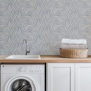 tropical boho palm leaf wallpaper in soft calm blue and white shown in removable peel and stick or prepasted. Perfect for modern coastal bathroom, powder room, nursery or laundry room accent wall.