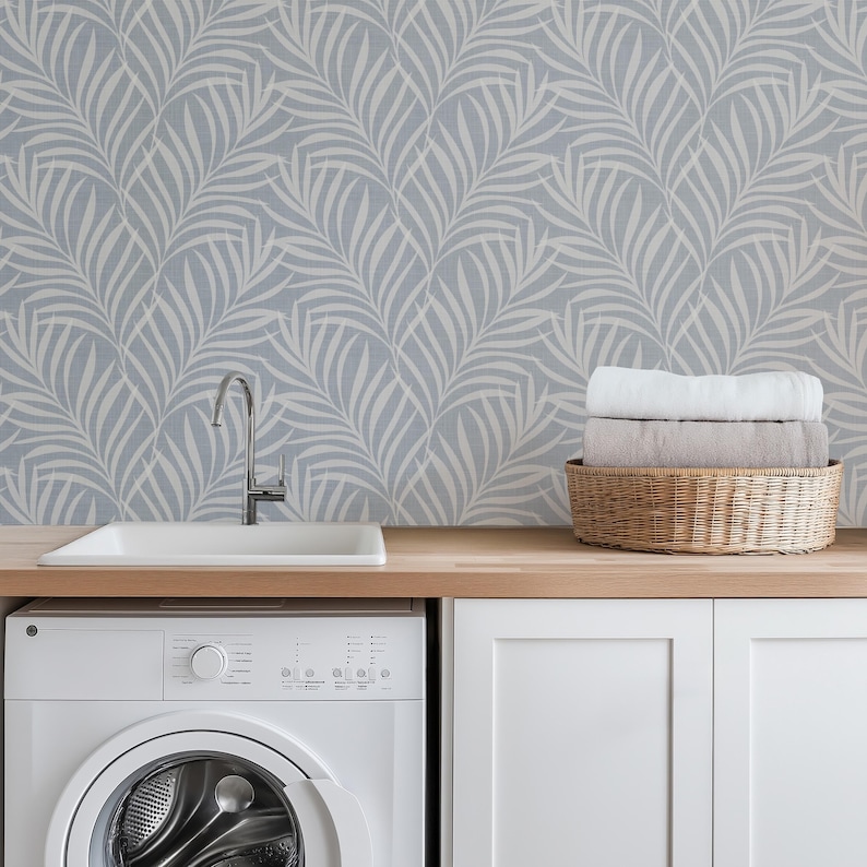 tropical boho palm leaf wallpaper in soft calm blue and white shown in removable peel and stick or prepasted. Perfect for modern coastal bathroom, powder room, nursery or laundry room accent wall.