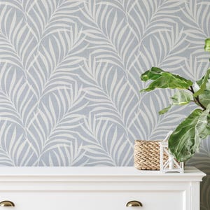 tropical boho palm leaf wallpaper in soft calm blue and white shown in removable peel and stick or prepasted. Perfect for modern coastal bathroom, powder room, nursery or laundry room accent wall.