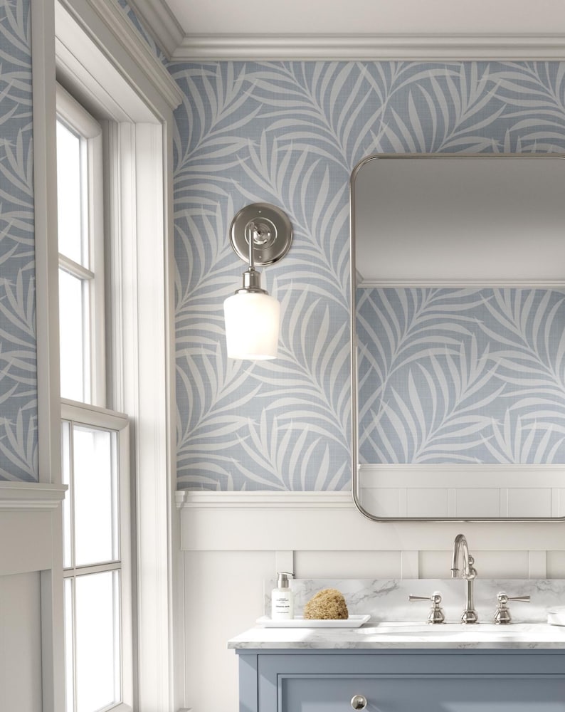 tropical boho palm leaf wallpaper in soft calm blue and white shown in removable peel and stick or prepasted. Perfect for modern coastal bathroom, powder room, nursery or laundry room accent wall.