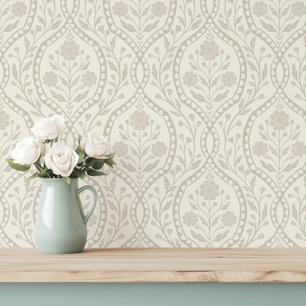 May include: A light green ceramic pitcher containing a bouquet of white roses. The pitcher has a curved handle and a smooth finish. The background features a repeating wallpaper pattern of beige floral motifs and vines on a cream surface.