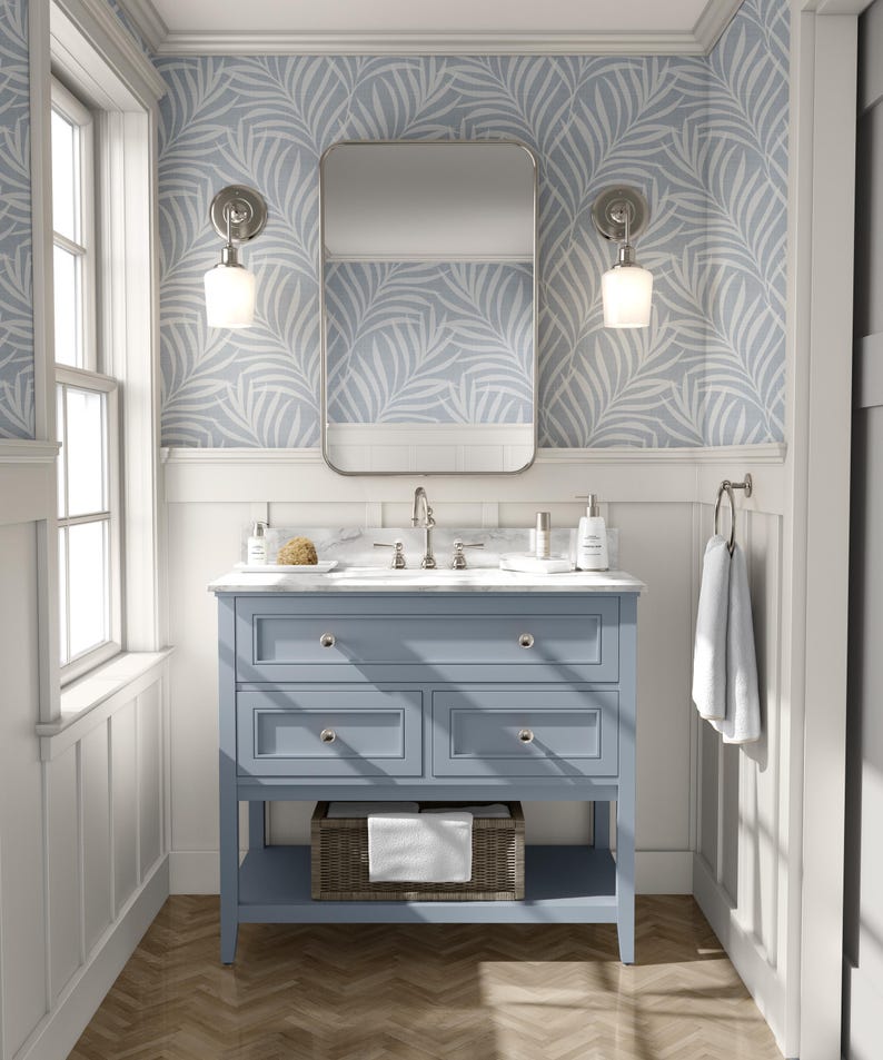 tropical boho palm leaf wallpaper in soft calm blue and white shown in removable peel and stick or prepasted. Perfect for modern coastal bathroom, powder room, nursery or laundry room accent wall.