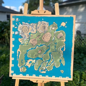 May include: A square canvas painting on a wooden easel depicting a stylized map with a blue ocean background, green landmasses, and tan mountain ranges. The map features a grid system with latitude numbers 10 through 90 and longitude numbers 10 through 90.