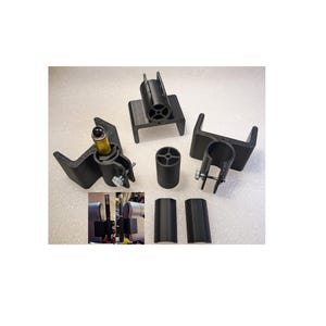 May include: A set of black plastic parts for a camera mount. The set includes two brackets, two cylindrical pieces, and a small piece with a screw. The parts are arranged on a white surface.