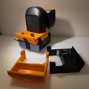 May include: A set of 3D printed camera accessories, including a black camera body holder, a black and orange camera lens holder, and an orange camera battery holder.