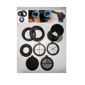 Op de afbeelding: Een set zwarte telescoopaccessoires van plastic, inclusief een buis, ringen en verschillende filters. De filters hebben verschillende vormen en maten, waaronder een cirkel, een kruis en een stervorm.