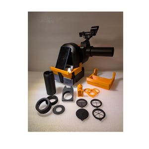 May include: A black and orange 3D printed smartphone adapter for telescopes. The adapter includes a phone holder, a telescope adapter, and a variety of filters.