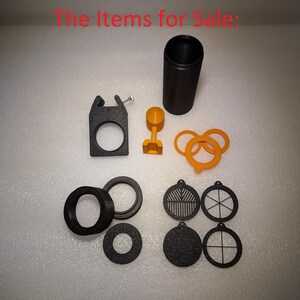 May include: A set of black plastic parts for a 3D printed project. The set includes a cylinder, a ring, a bracket, a small round piece, and several round discs with different patterns.