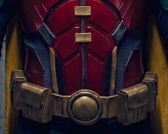 May include: A superhero costume featuring a red chest plate with a gold R emblem, metallic green shoulder and forearm armor, and a gold utility belt. The outfit includes a dark blue long-sleeve base layer, a yellow cape, and a green eye mask.