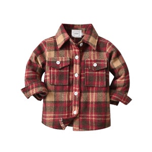 May include: A red and brown checked flannel shirt with long sleeves and button fastening. The shirt has two flap pockets on the front.