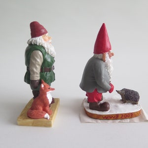 May include: Two hand-painted gnome figurines, one with a red hat and a hedgehog, the other with a green hat and a fox. The base of the gnome with the red hat reads "WWF 2003".