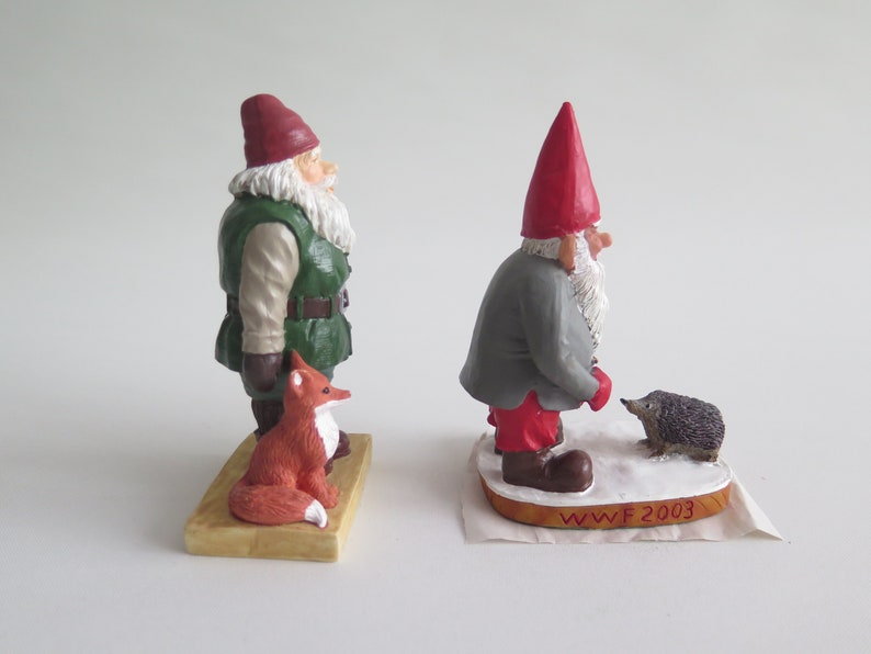 May include: Two hand-painted gnome figurines, one with a red hat and a hedgehog, the other with a green hat and a fox. The base of the gnome with the red hat reads "WWF 2003".