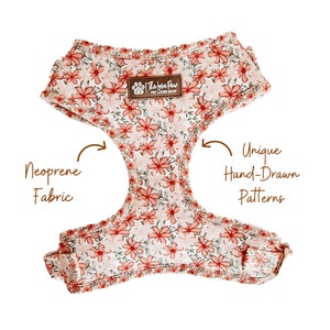 May include: A pink and green floral dog harness with a brown label that says "The Love Paws Pet Lover Shop". The harness is made of neoprene fabric and features a unique hand-drawn pattern.
