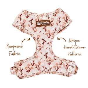 May include: A pink and brown floral dog harness made of neoprene fabric with the text "The Love Paws Pet Lover Shop" on the front. The harness features unique hand-drawn patterns.
