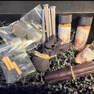 May include: A white ceramic mug with a black handle and the text "But First, Coffee" in a black, handwritten-style font. The mug is on a white surface.