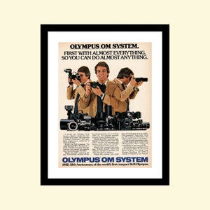 Puede incluir: Un anuncio impreso vintage para la cámara Olympus OM System. El anuncio presenta a un hombre sosteniendo una cámara y el texto "Olympus OM System. Primero con casi todo, para que puedas hacer casi todo." El anuncio también incluye el texto "1982: 10º aniversario del primer SLR compacto del mundo. Olympus."