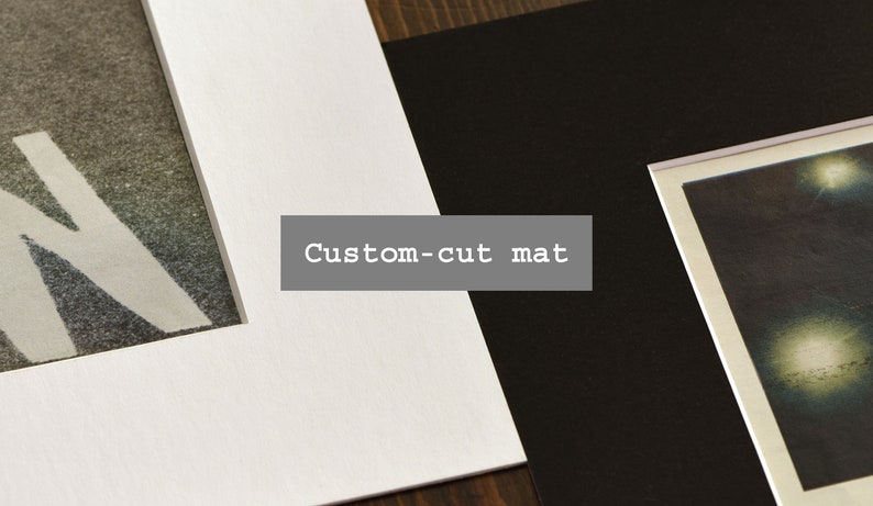 May include: A white mat board with a custom-cut mat opening, next to a black mat board with a picture of a night sky with stars.