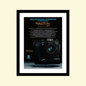 Puede incluir: Una cámara réflex digital autofocus Minolta Maxxum 9000 negra con una lente plateada. La cámara está sobre una superficie negra con un fondo blanco. El texto "Minolta Maxxum 9000 Autofocus SLR System" está impreso en blanco sobre un fondo negro.