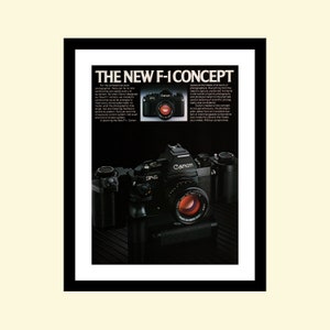 Puede incluir: Una cámara Canon F-1 negra con una lente negra y un anillo rojo alrededor de la lente. La cámara está sobre una superficie negra. El texto "THE NEW F-ICONCEPT" está en la parte superior de la imagen. El texto "Canon" está en la cámara.