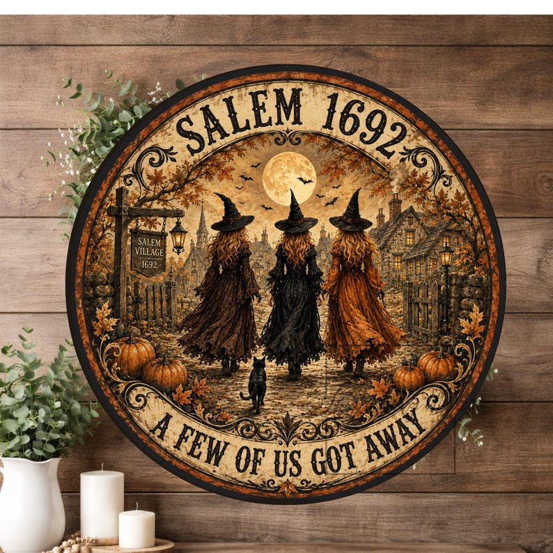 May include: A round wall sign featuring a scene of three witches in pointed hats walking toward a village under a full moon. The text reads SALEM 1692 at the top and A FEW OF US GOT AWAY at the bottom. The image includes pumpkins and a black cat.