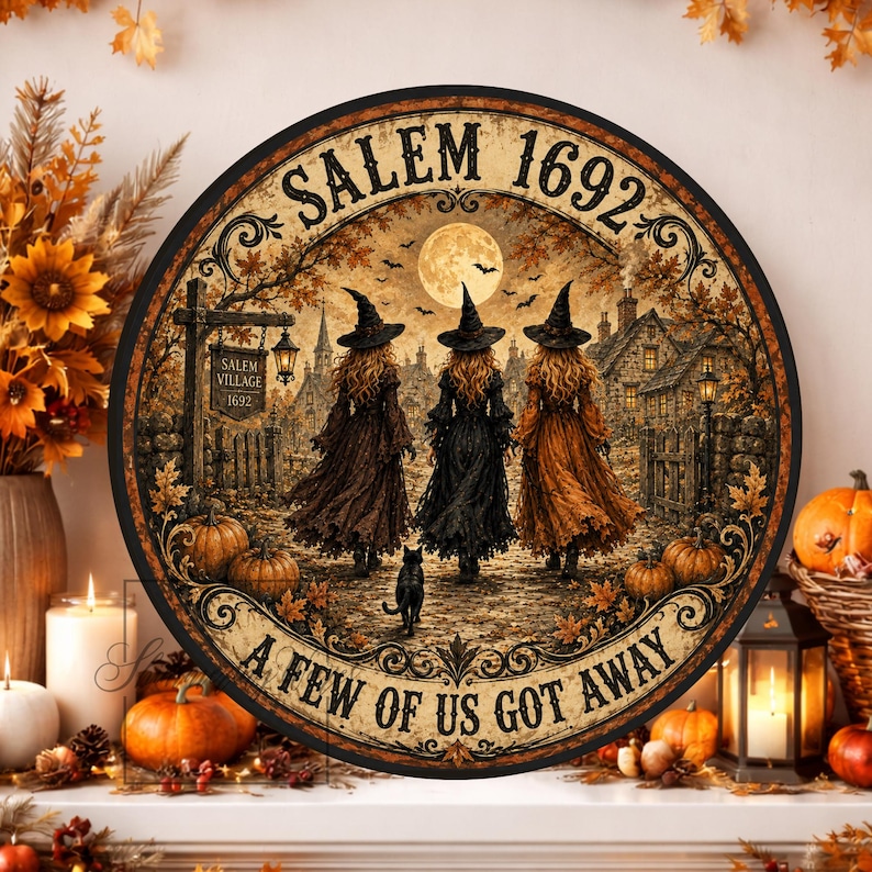 May include: A circular wall sign featuring a scene of three witches in pointed hats walking toward a village under a full moon. The text reads SALEM 1692 at the top and A FEW OF US GOT AWAY at the bottom. The artwork includes autumn leaves and a black cat.