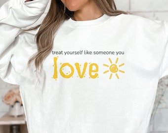 May include: White sweatshirt with a yellow graphic that says "treat yourself like someone you love" with a sun graphic next to the word "love".