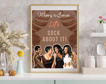May include: A framed art print with the text "Waiting to Exhale" and "Let's Sock About It!" features four women. The print has a gold frame and is displayed on a white shelf with decorative items.