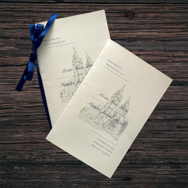 May include: Two cream wedding programs tied with a blue ribbon. The programs display a church illustration and text: "Welcome to the Wedding of Lexie Rose Love and Hunter Joseph Hearst" and the date October 18, 2025.