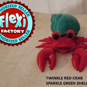 May include: A red sparkle crab with a green sparkle shell. The crab has a happy expression and large black eyes. The text "TWINKLE RED CRAB SPARKLE GREEN SHELL" is below the crab.