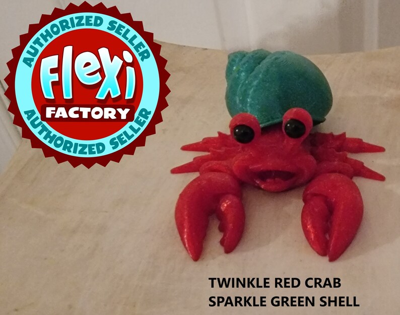 May include: A red sparkle crab with a green sparkle shell. The crab has a happy expression and large black eyes. The text "TWINKLE RED CRAB SPARKLE GREEN SHELL" is below the crab.