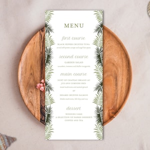 May include: A white menu card with a tropical theme. The menu card has a green border with palm leaves and the text "MENU" in a brown font. The menu items are listed in black font and include "first course", "second course", "main course", and "dessert".