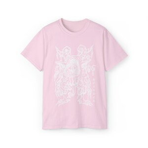 May include: A pink t-shirt with a white graphic print of a creature with multiple eyes and limbs. The text "SORCERER" is printed vertically on the right side of the graphic.