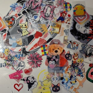 May include: A collection of iron-on patches featuring various designs, including cartoon characters, animals, and text. The patches are on a white background and are ready to be ironed onto fabric.