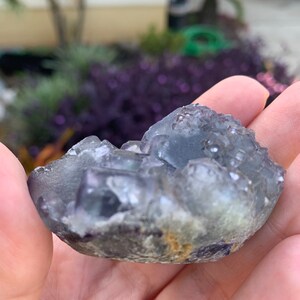 Op de afbeelding: Een kleine, onregelmatig gevormde, doorschijnende blauwgrijze fluorietkristalgroep. De kristal heeft een ruw, getextureerd oppervlak met zichtbare kristallijne structuren en een vleugje geelbruine kleuring.