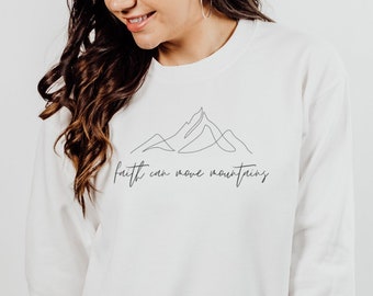 May include: White long-sleeve sweatshirt with a black mountain graphic and the text "faith can move mountains".