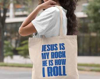 May include: A beige tote bag with blue text that reads "Jesus is my rock he is how I roll".