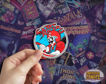 May include: A circular sticker featuring a cartoon character in a red racing helmet and overalls, driving a kart. The sticker has the text "Go Kart Racer Co." and is set against a blue and white background. The background is a collage of comic book covers.