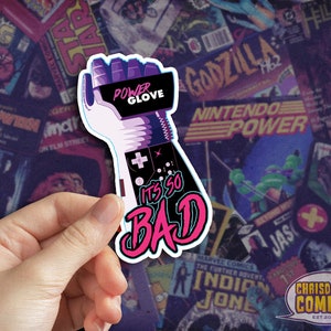 May include: A sticker featuring a stylized illustration of a purple and pink robotic arm with a controller and the text "Power Glove It's So Bad".