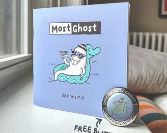 May include: A blue book with the title "Most Ghost" and an illustration of a ghost wearing sunglasses and a hat, floating on a blue and white polka dot inner tube. The book is on a white surface with a silver pin that says "Official Most Ghost Spiritual Supporter" on it.