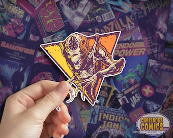 May include: A sticker featuring a purple and yellow alien creature with sharp teeth and claws, in a triangular shape with a yellow and orange background.